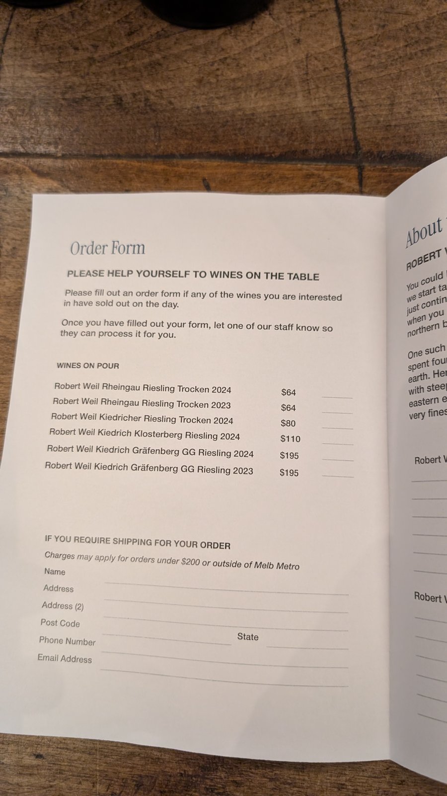 The Rathdowne Cellars order form, open on a wooden table, listing the six Robert Weil wines on pour, priced from $64 for the Rheingau Riesling Trocken to $195 for each vintage of the Kiedrich Gräfenberg GG