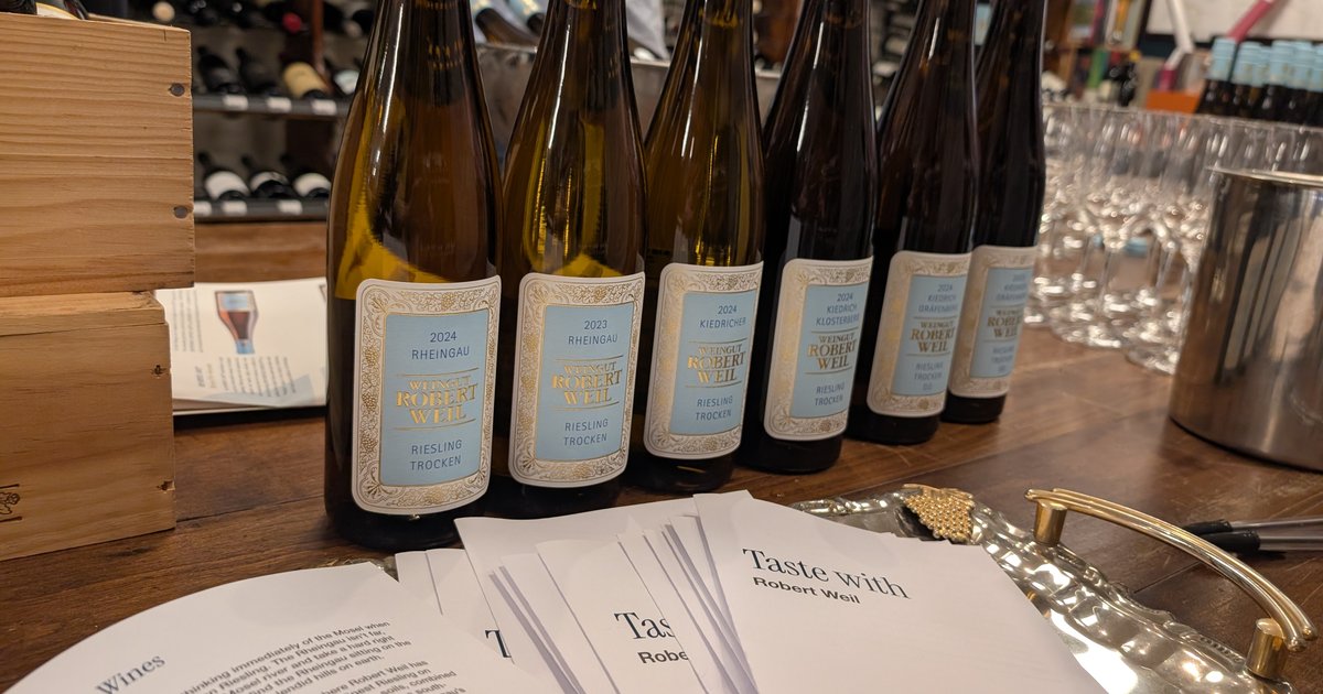Six Robert Weil Riesling bottles lined up on a wooden counter at Rathdowne Cellars, pale blue labels running from the 2024 Rheingau to the Kiedrich Gräfenberg, with a fan of Taste with Robert Weil booklets in front