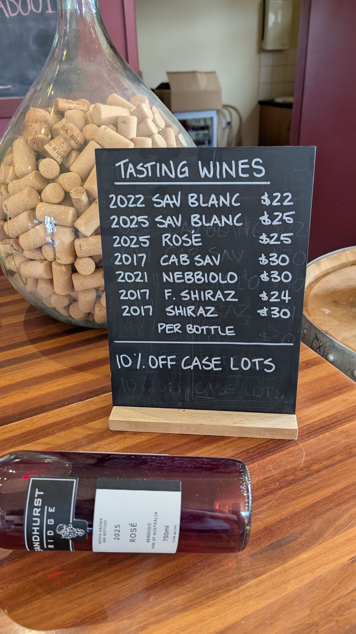 The cellar door blackboard listing the seven tasting wines and their per-bottle prices, from the 2022 Sauvignon Blanc at twenty-two dollars to the 2017 Shiraz at thirty
